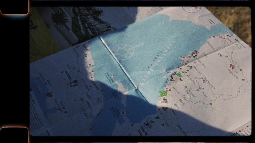 A traveler unfolds a paper map of a coastal destination, captured in a warm, vintage film style