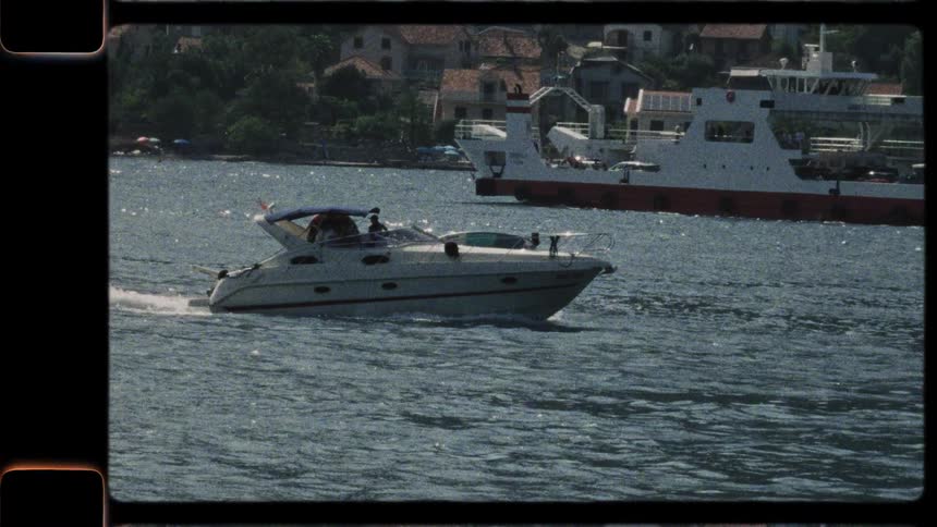 A classic motor yacht glides across the sun-drenched sea, captured on vintage film
