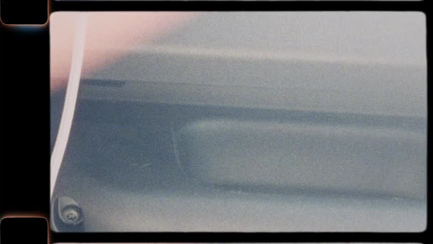 Super 8mm vintage film aesthetic captures the abstract blur of a passing car door