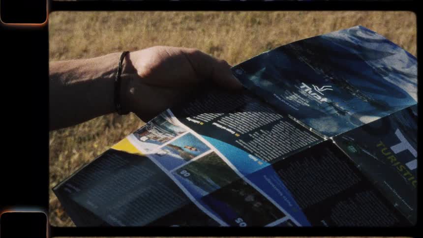 A traveler's hands unfold and then fold a tourist map of Tivat, Montenegro, on a sunny day in a vintage-style clip
