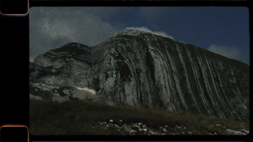 A vintage 8mm film panning shot reveals the rugged and beautiful landscape of a high-altitude mountain pass