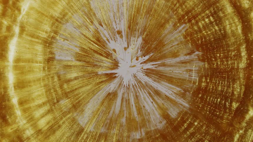 An abstract background of shimmering gold liquid slowly solidifying and forming textured rings from a central point