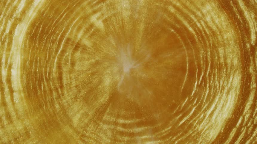 A shimmering golden liquid swirls and ripples in slow motion, creating a mesmerizing abstract background