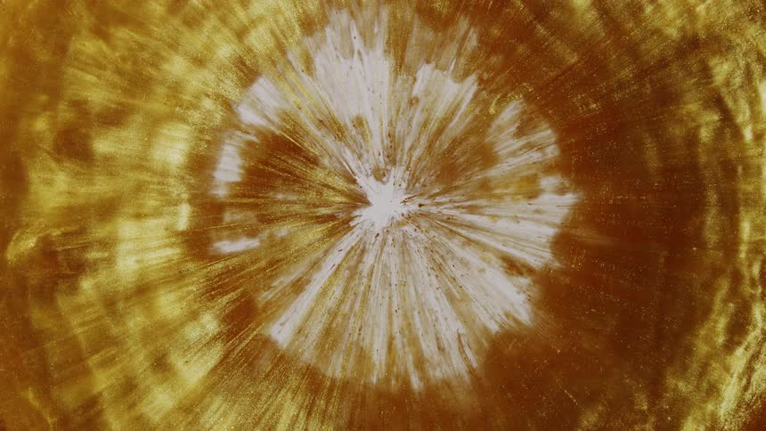 Hypnotic ripples of liquid gold expand slowly from a bright white starburst in a captivating abstract display