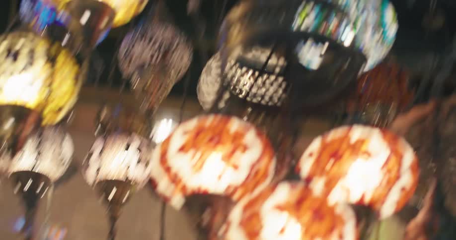 A dizzying, mesmerizing low-angle shot of colorful mosaic Turkish lanterns hanging in a market stall