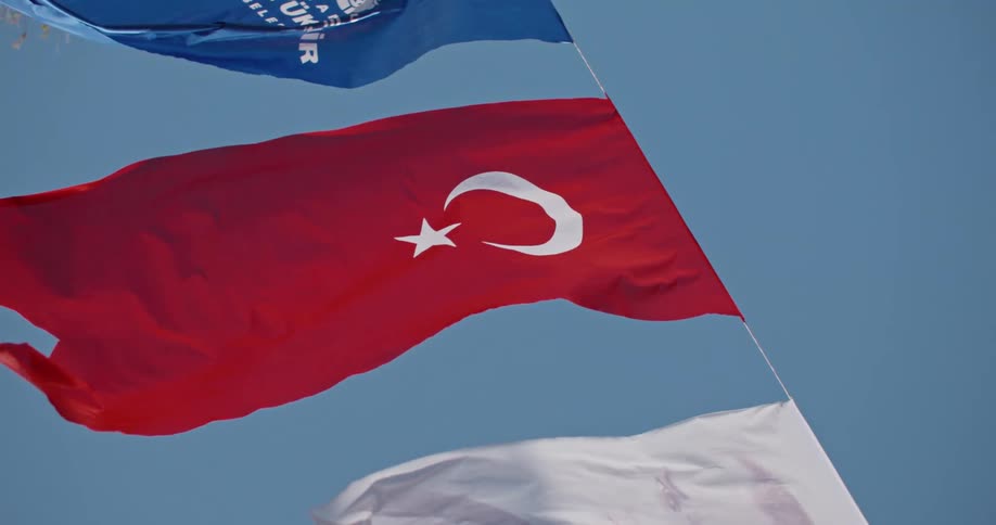 Slow-motion vertical video of the Turkish national flag, the Istanbul city flag, and an Atatürk flag waving together under a clear blue sky