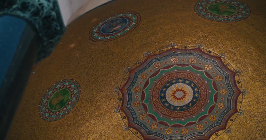 Low angle pan across the detailed golden mosaic ceiling of a magnificent historic building
