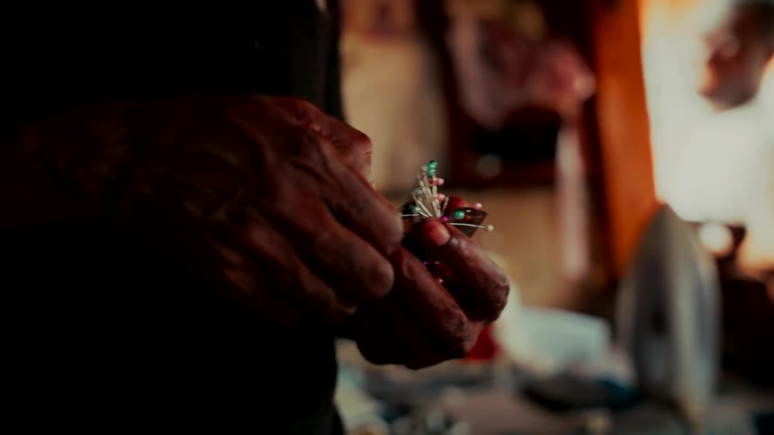 Close up of a tailor's hands picking a colored pin out of a bundle in a workshop