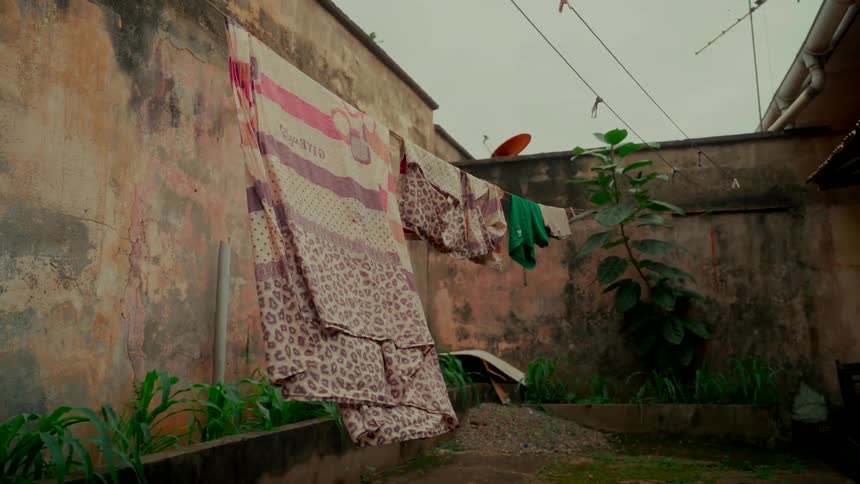 Laundry hangs to dry on a clothesline in a dilapidated urban courtyard under a grey sky