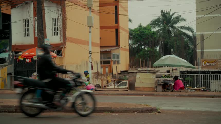 Slow motion shot of cars and motorcycles driving on a bustling street in an African city