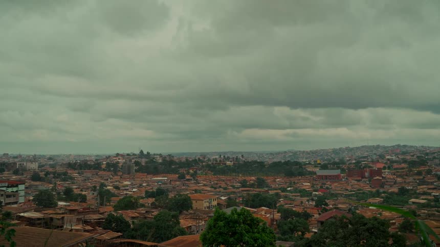 An expansive view of a densely populated city with brown rooftops under a heavily overcast sky