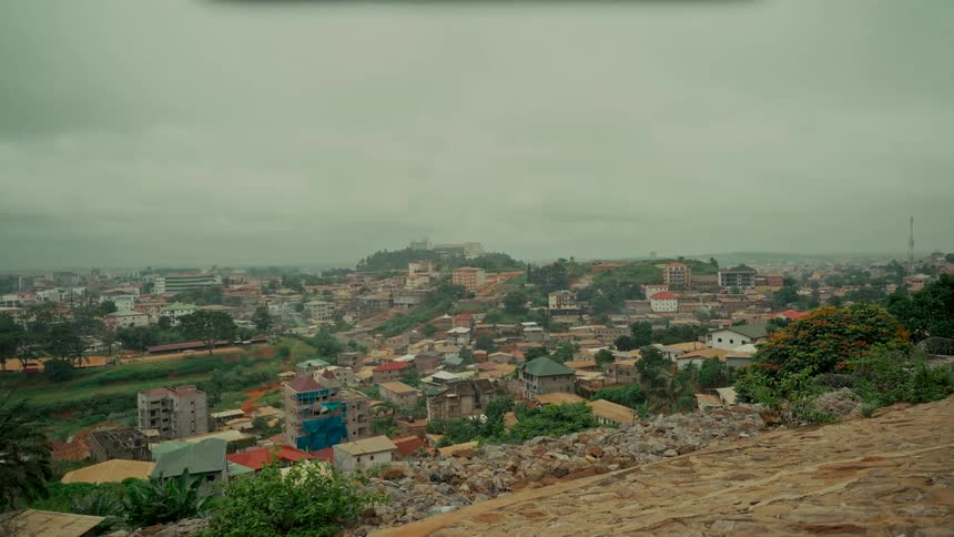 A sprawling city nestled amongst lush green hills on an overcast day