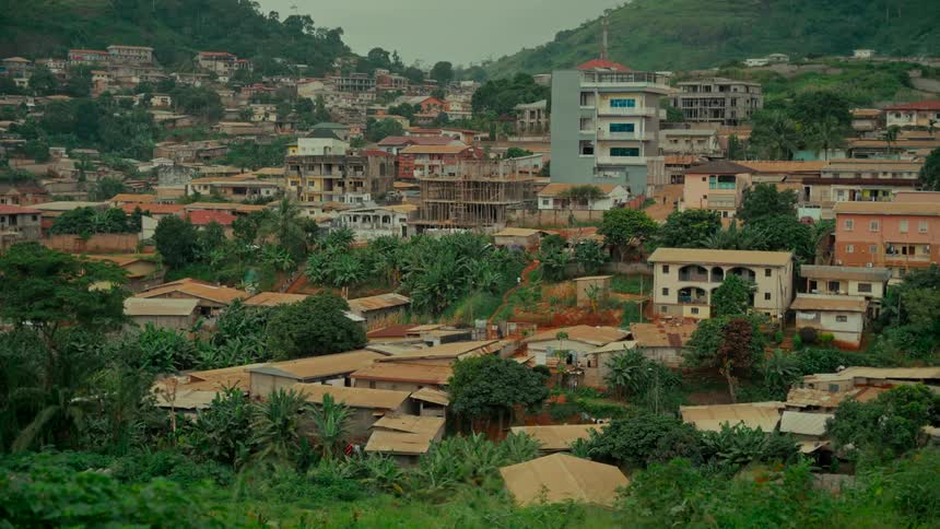 A wide, static view of a densely populated town built on a lush green hillside