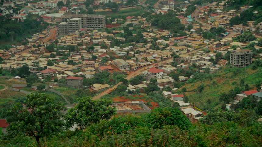 Wide establishing shot of a town built on rolling green hills with diverse architecture