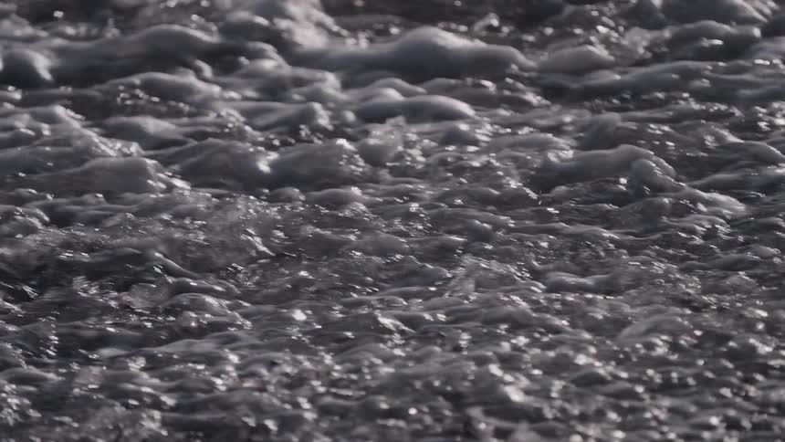 Slow motion close up of churning wastewater with foam and bubbles