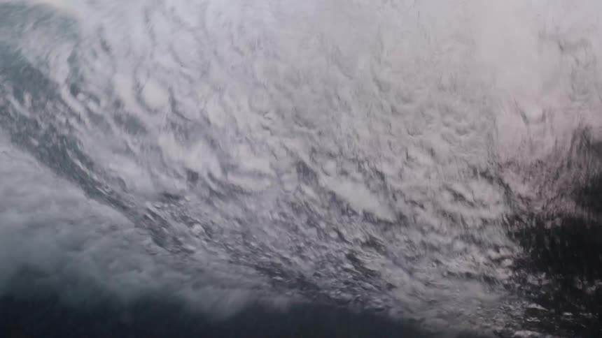 An underwater view captures the power of a breaking ocean wave in slow motion