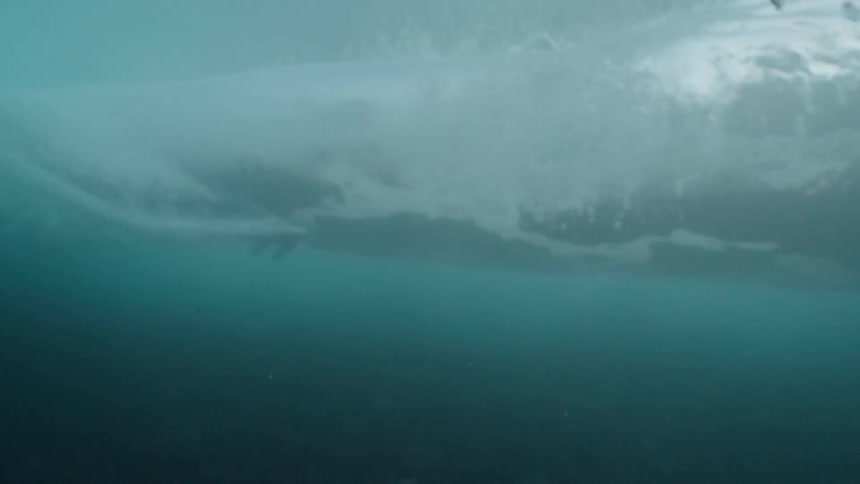 An artistic slow motion underwater view of a beautiful turquoise ocean wave breaking