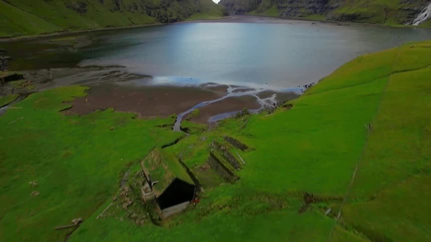 The green hill leads to a house by the water