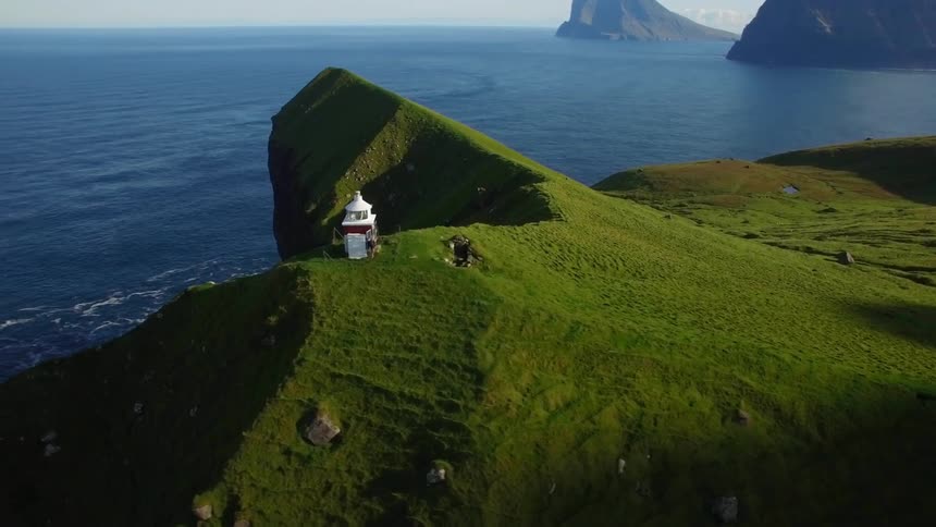 A tower sits on top of a cliff by the water