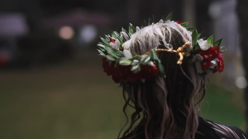 A slow motion close up from behind a woman wearing a traditional Hawaiian lei po'o at an evening event