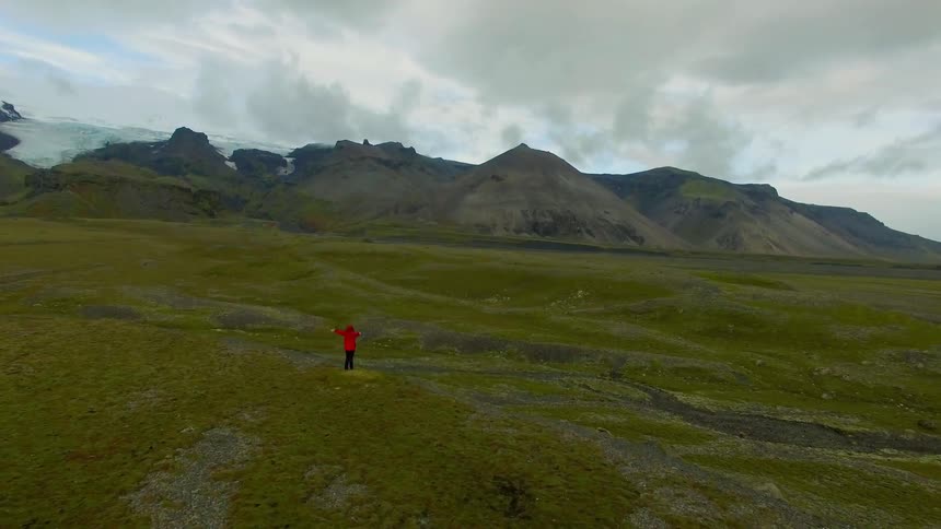 A person stretches their arms out to the sides as they stand in a natural setting