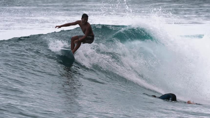 A surfer skillfully rides inside the barrel of a powerful ocean wave in dramatic slow motion