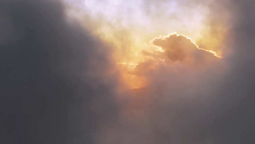 Heavenly golden sun rays break through a gap in dark, moody storm clouds