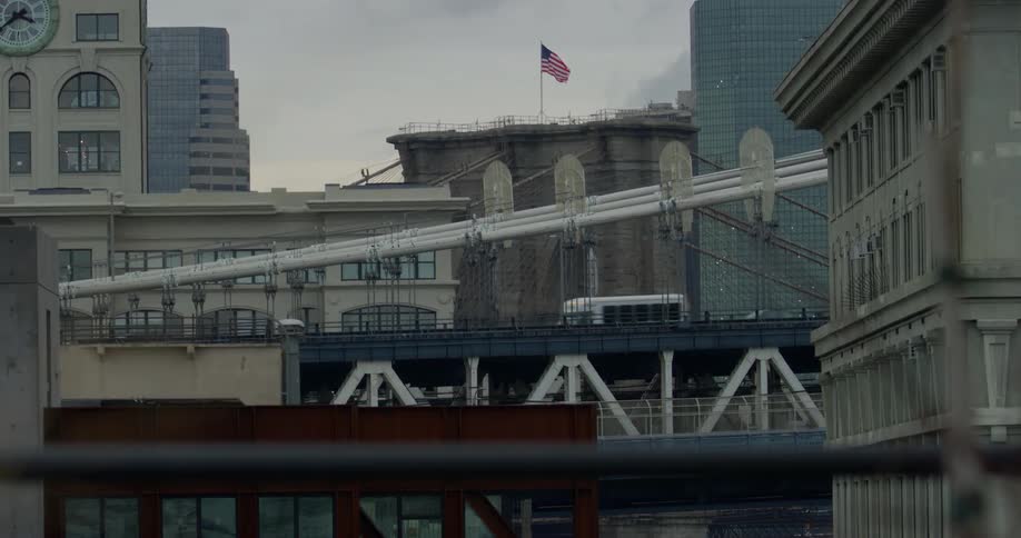An american flag flaps in the breeze as cars pass by on a bridge near it