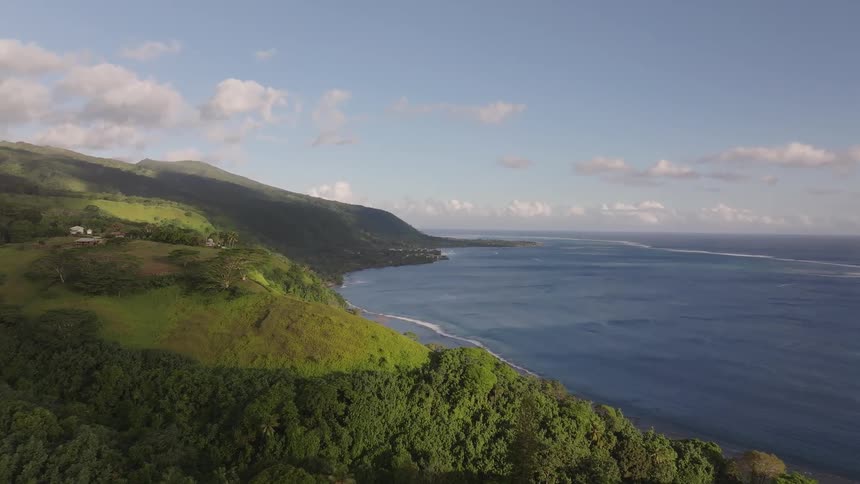 Aerial drone footage captures the breathtaking beauty of a tropical island with lush green mountains and a vibrant blue ocean