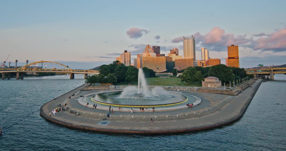 A scenic wide shot of the fountain at Point State Park in Pittsburgh, Pennsylvania, with the city skyline in the background at dusk