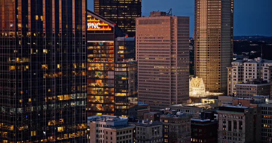 Zooming out from the illuminated windows of downtown office buildings and skyscrapers at dusk