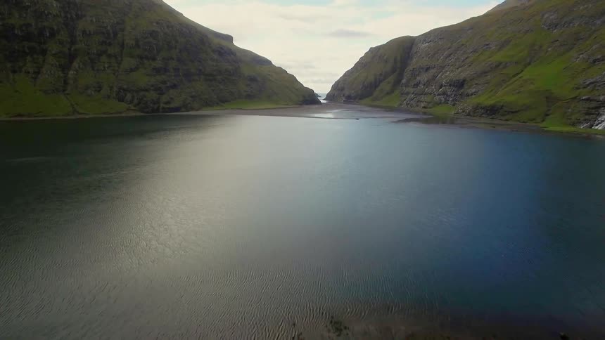 A single houses sits on a cliff by the lake