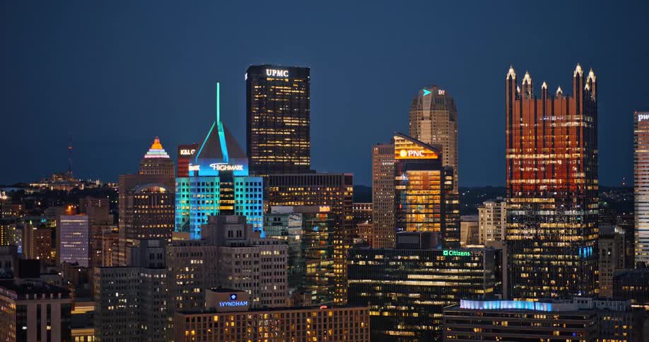 A slow zoom out of the brightly illuminated Pittsburgh, Pennsylvania city skyline at dusk