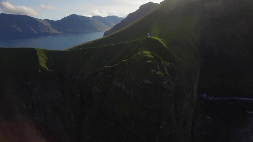 A lighthouse sits atop a cliff next to the ocean