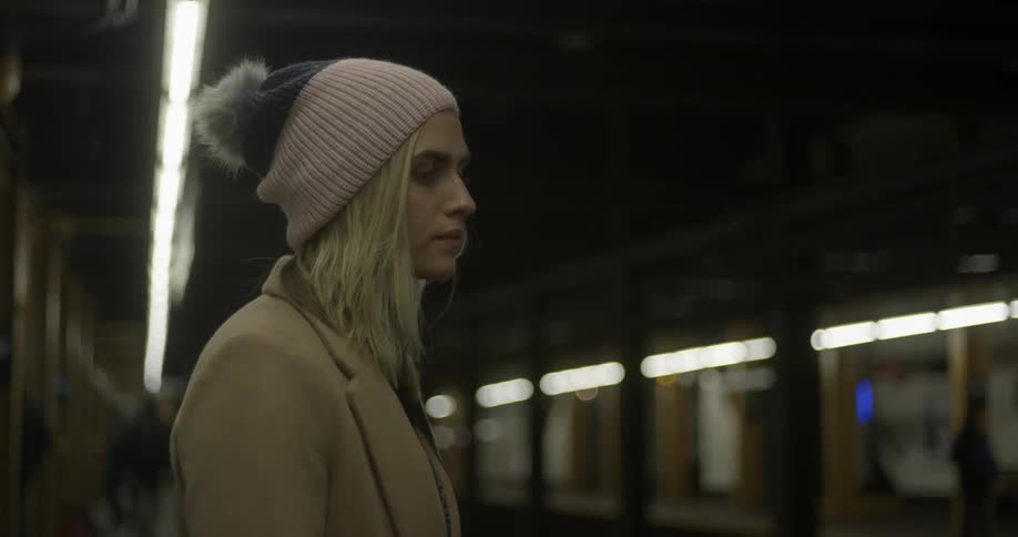 A woman stands in thought as she waits in a subway station