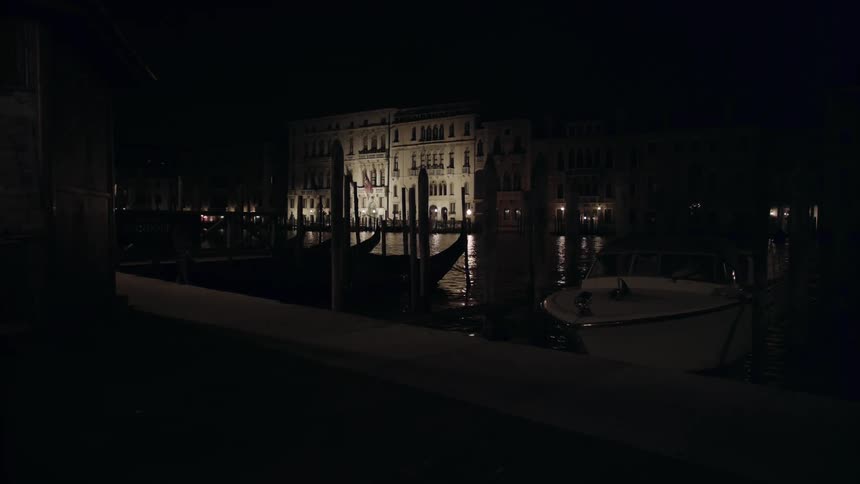 A boat docked in a canal bobs on the water