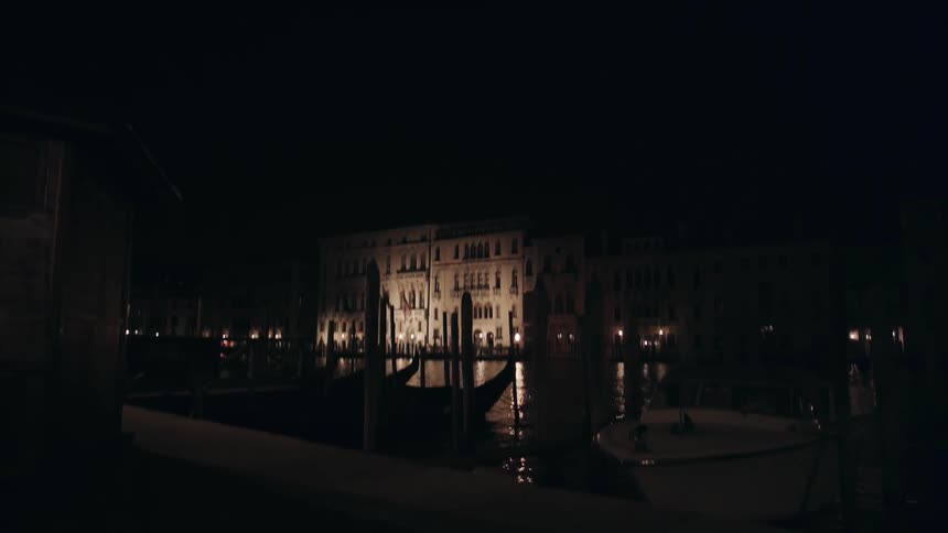 Boats float and bob at a dock in an old city at night