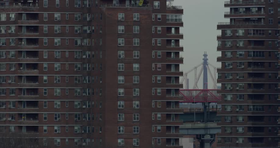 Vehicles pass on a bridge behind two large apartment buildings