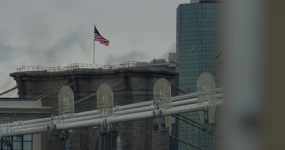 The american flag on top of a city building on a cloudy day