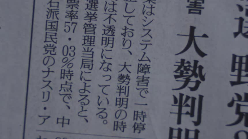 Close up vertical shot of someone scanning through a Japanese newspaper