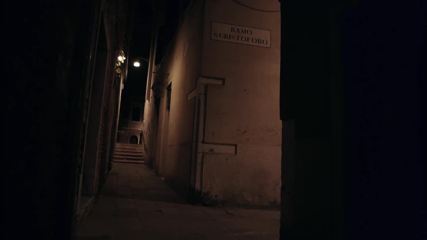 The alley is dark with only a single light