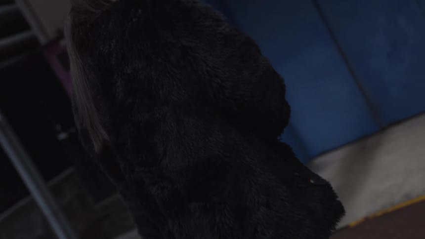 A slow tilt down reveals a fashionable woman's full outfit, from her black fur coat to her unique architectural heels