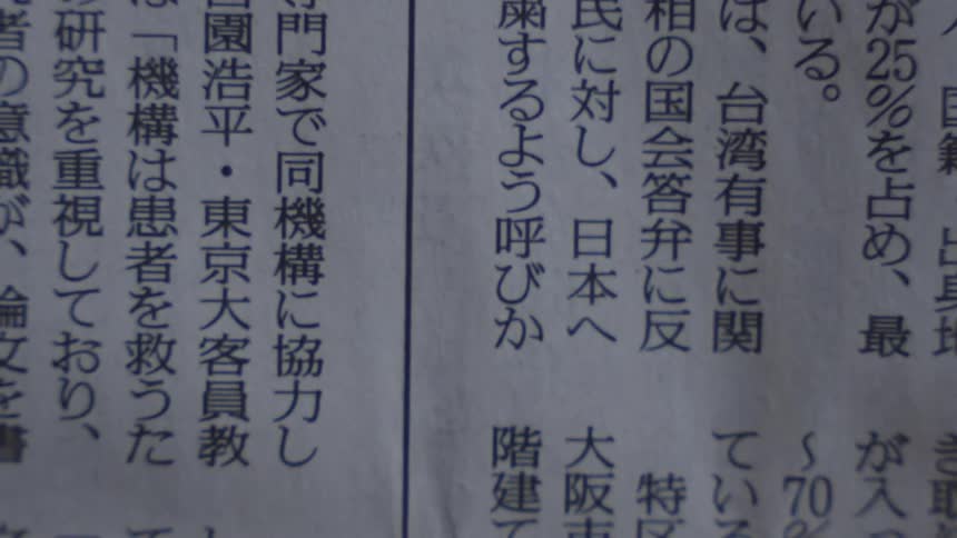 Extreme close-up of a person quickly scanning through the text of a Japanese newspaper