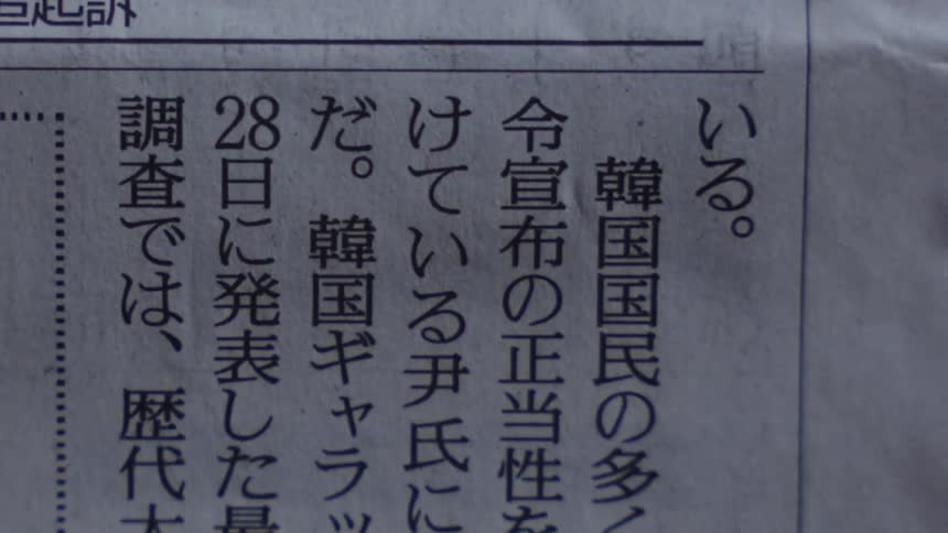 A close-up panning shot across the articles of a Japanese newspaper
