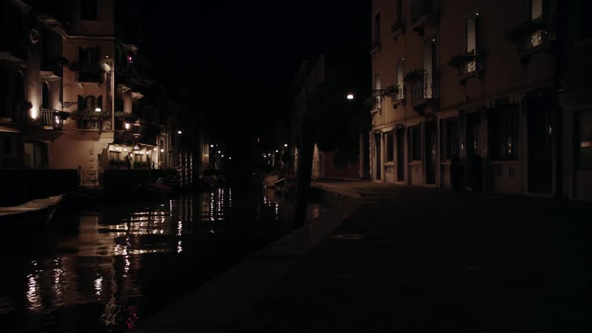 A canal has buildings on each side at night