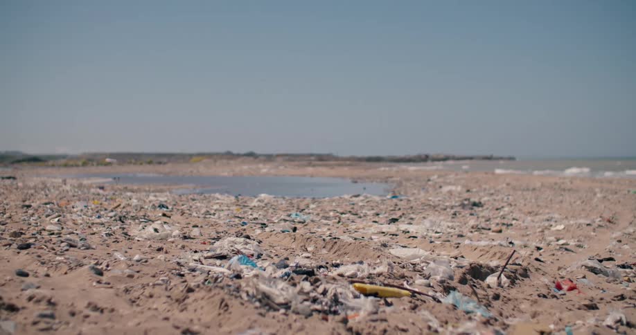 A sandy beach is completely covered in plastic garbage and debris, highlighting the severe issue of environmental pollution