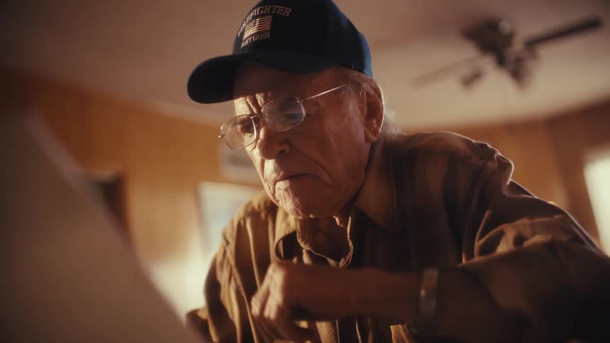 A retired firefighter sits at his table, distressed while reviewing his paperwork and finances