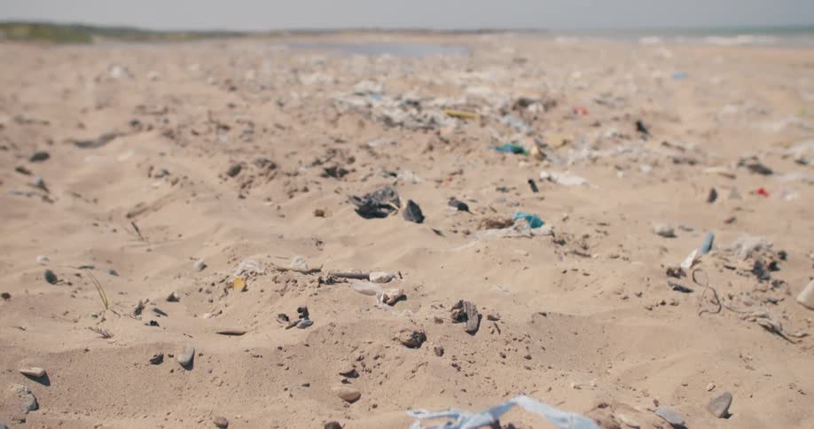 A slow revealing shot shows the devastating impact of plastic pollution on a once pristine sandy beach