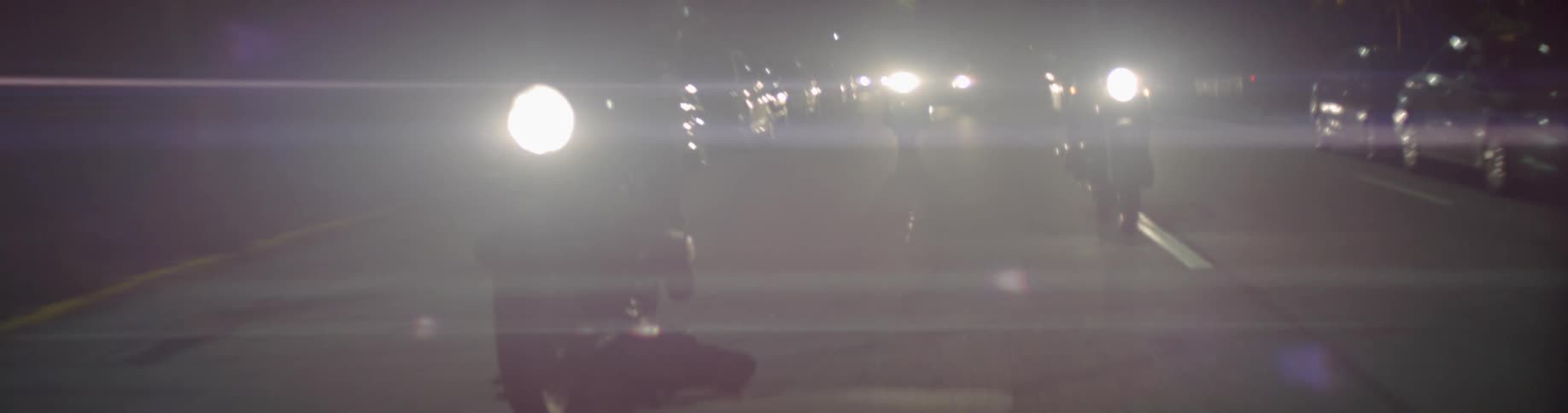 Motorcyclists riding on a city street at night