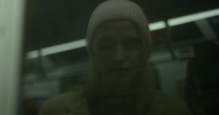 A woman taking a photograph on a train is reflected in the window